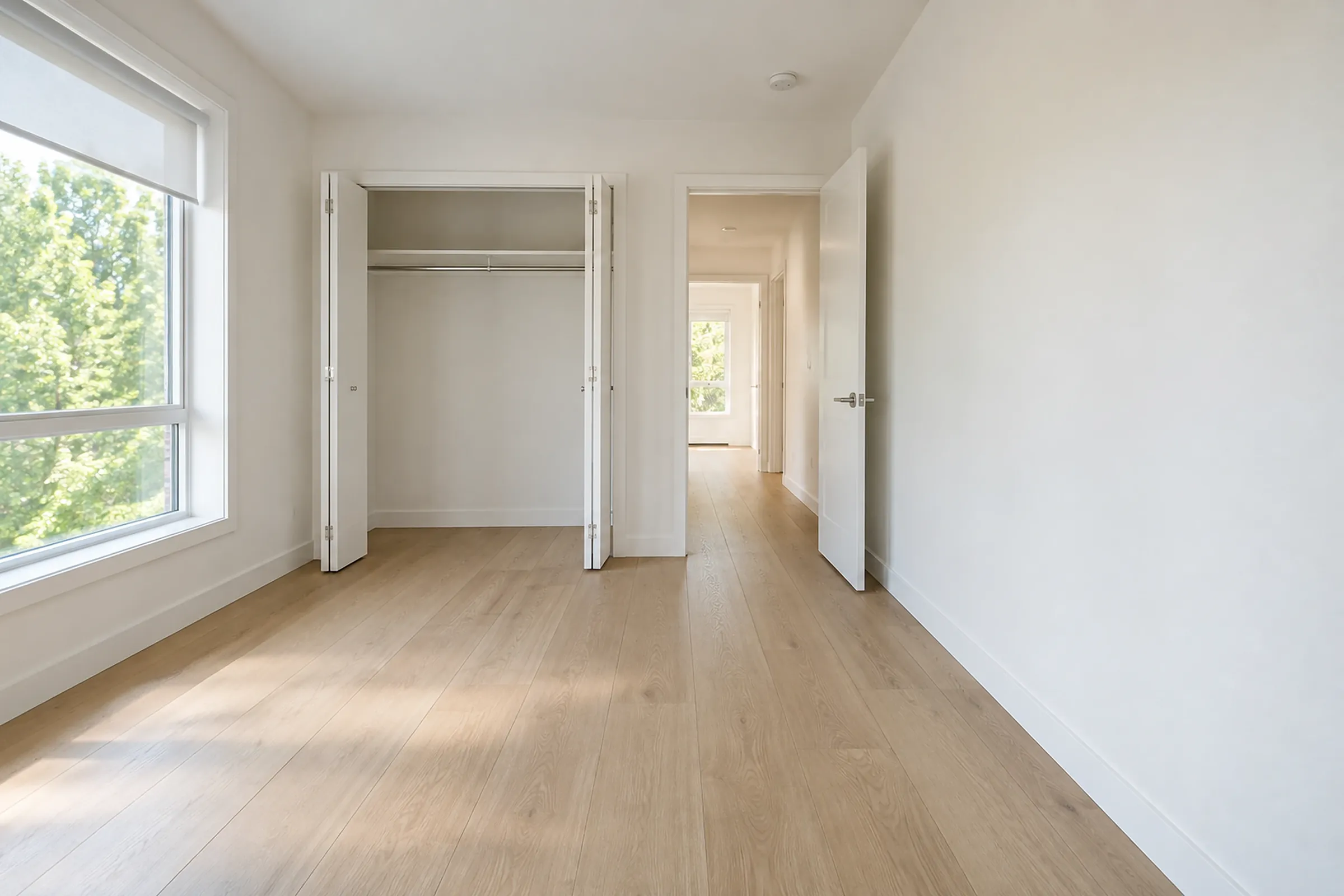 An empty condo bedroom with the closet doors open on a bare, clean closet